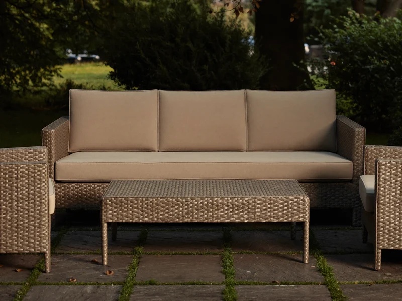 Illustriertes Lounge-Set aus Geflecht mit Sesseln und beigen Kissen im Abendlicht