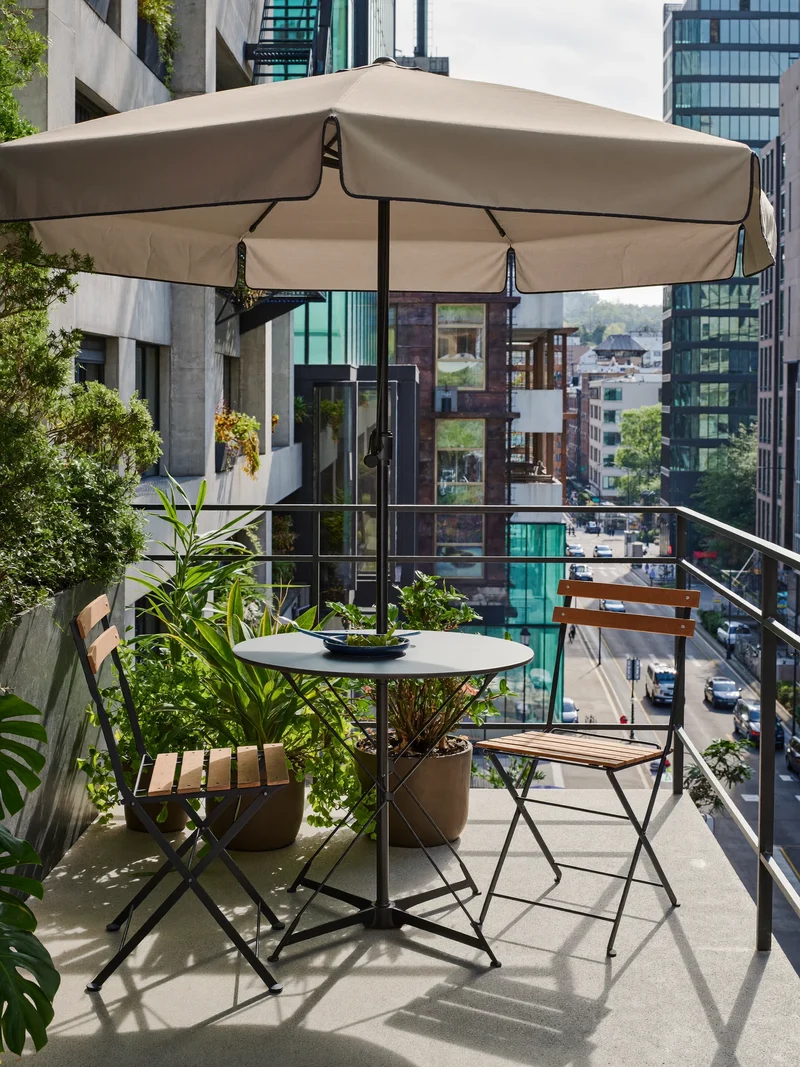 Illustrierter Ampelschirm über einem Bistrotisch auf einem begrünten Stadtbalkon